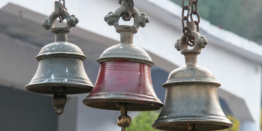 Three hanging temple bells made of brass, symbolising spirituality and tradition in a serene
