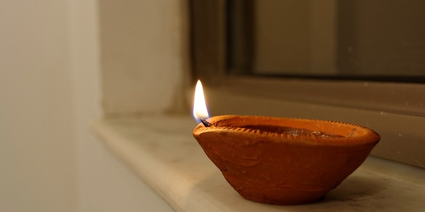 Image of a diya lit with white background in a temple - explore the temple and its surroundings