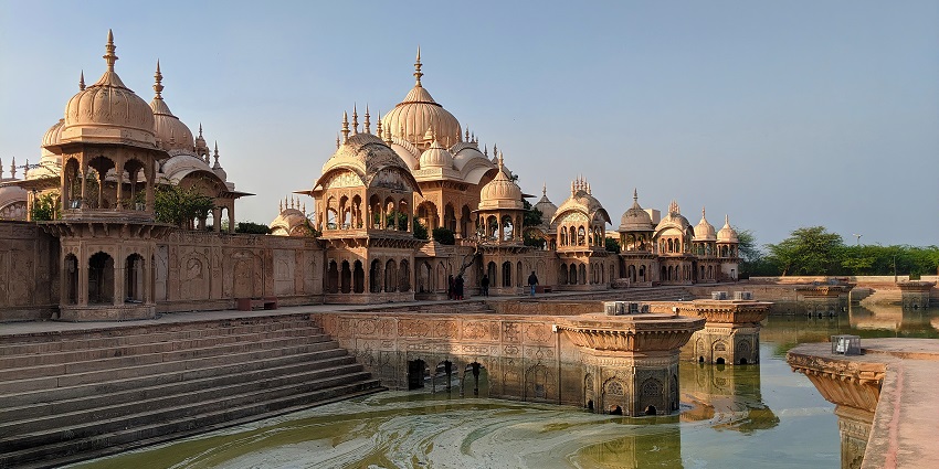 A picture of a traditionally built palace with a small water body flowing in front.