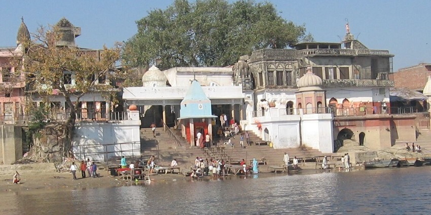 A picture of a ghat in Uttar Pradesh with people sitting on the stairs and enjoying the river water flowing
