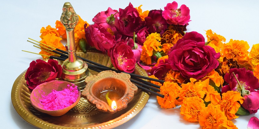 Image of a pooja thali decorated with flowers, diya, incense stick and other items