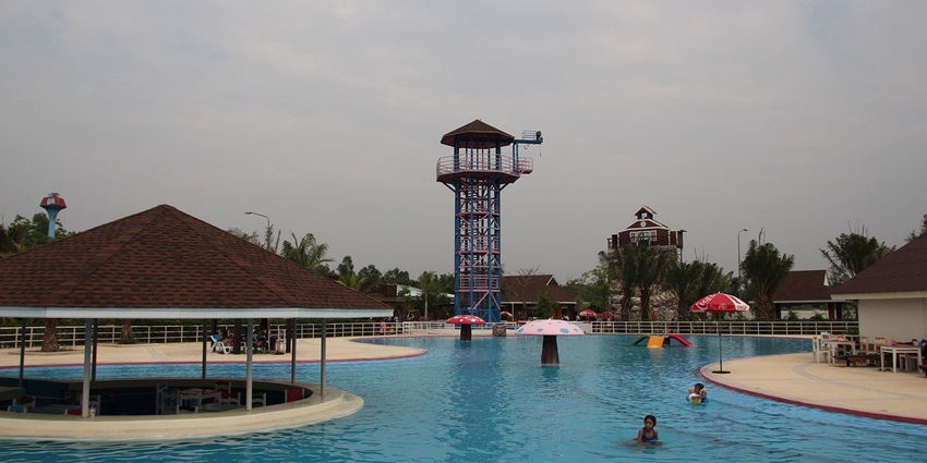 Vibrant water park with large pools, water slides, and palm trees under a sunny, clear sky