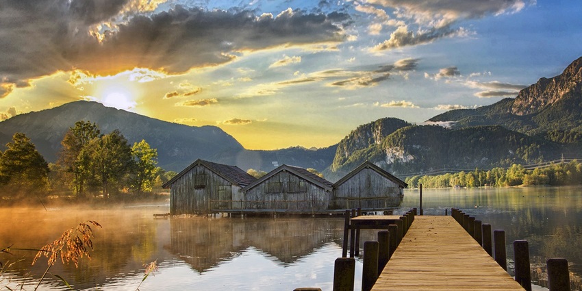 A lake reflects the sky, surrounded by lush greenery and calm waters