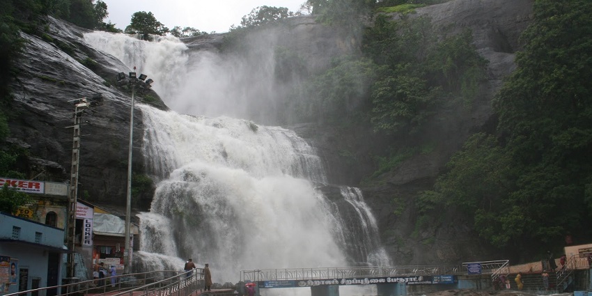 An image showcasing the scenic Courtallam Waterfalls gracefully flowing over rugged rocks.