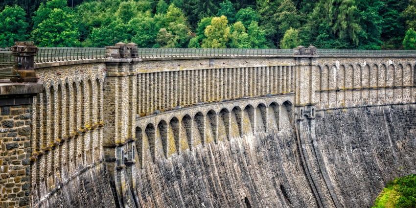 Concrete dam wall and barrier reflecting water, a tourist attraction.