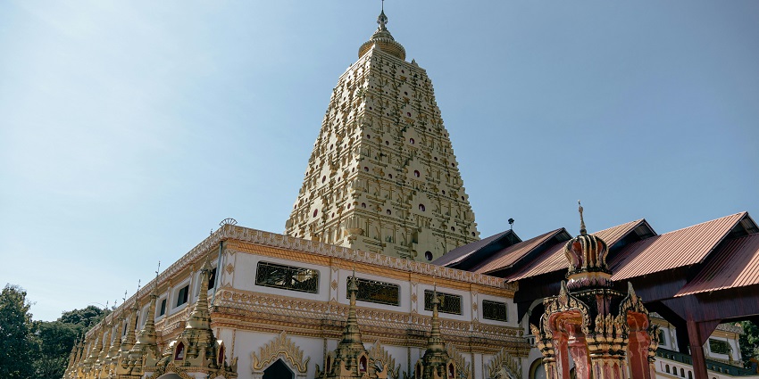 Golden temple tower reaching toward a clear sky, showcasing intricate architecture and spiritual grandeur.