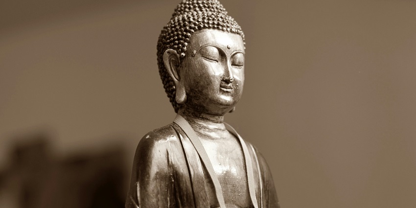 A golden Buddha statue with a gentle smile in a Buddhist centre in a pose of meditation.
