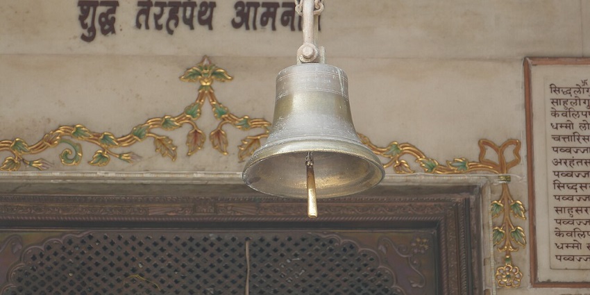 Large temple bell with intricate engravings, hanging from a wooden beam