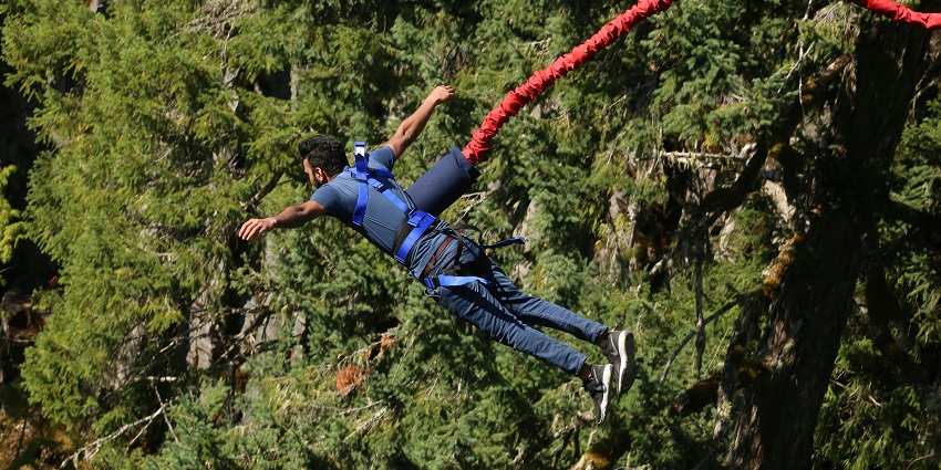 A stunning view of a person bungee jumping from a cliff harnessed with a rope.