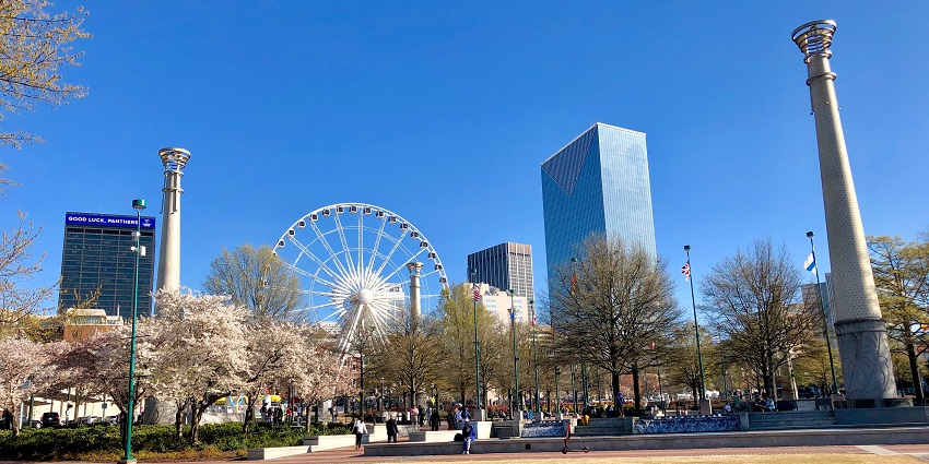 Trees, tall buildings, people and a Ferris wheel seen in Centennial Olympic Park.