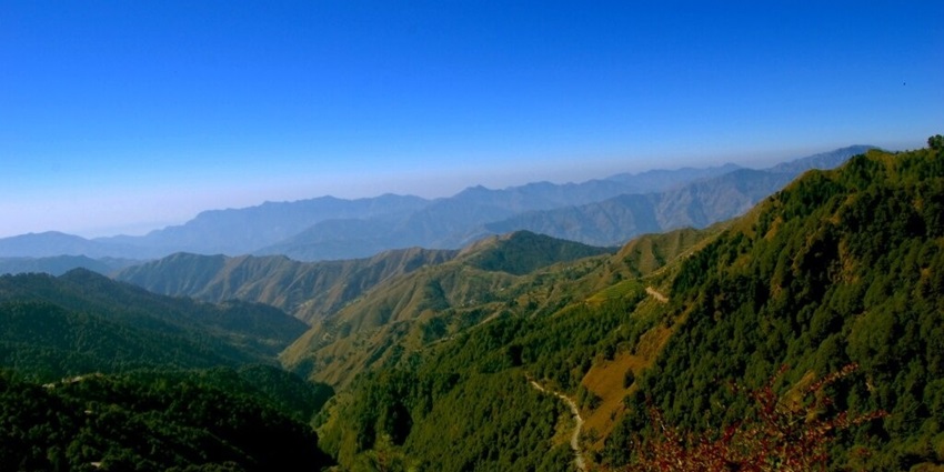 A picture of a mountain range under a clear blue sky, taken from another mountain