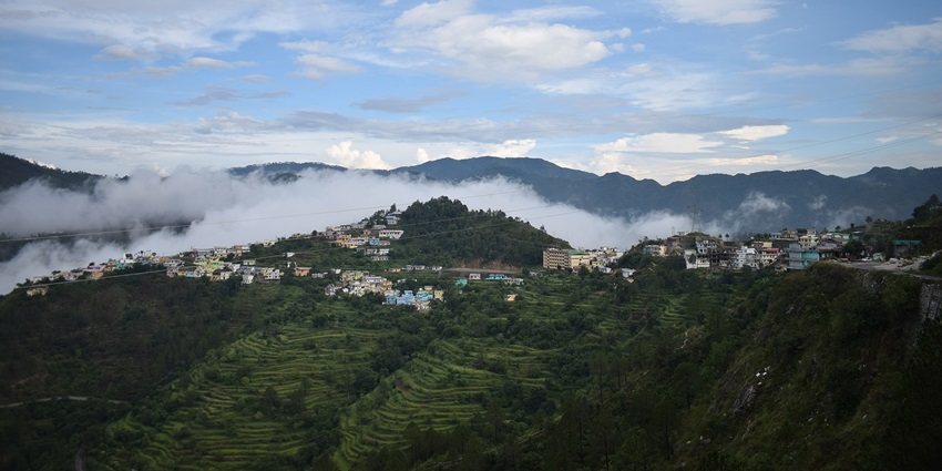 Scenic view of Chamba town with forested hills and distant Himalayan backdrop.