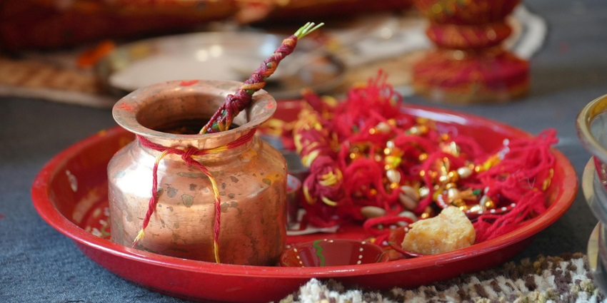 Decorative pooja thali with lit diya, vibrant flowers, and ritual items arranged for prayer
