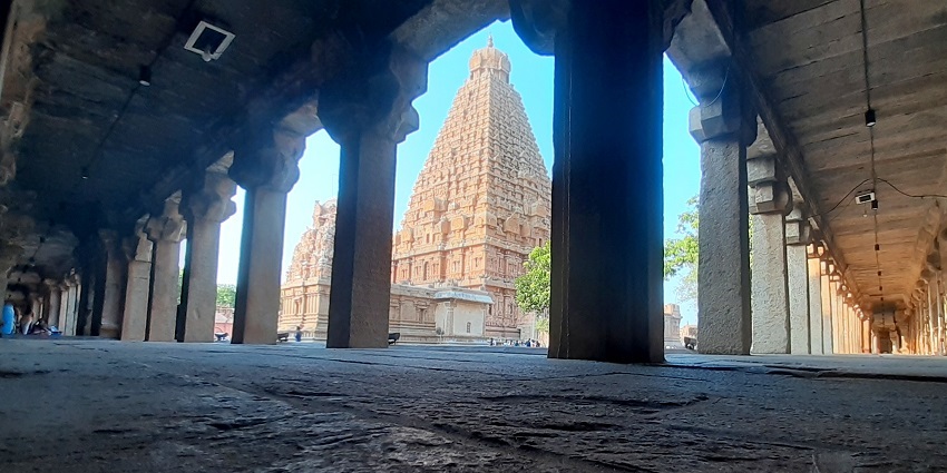 Chennimalai Murugan Temple's towering gopuram with intricate carvings, framed by pillars.
