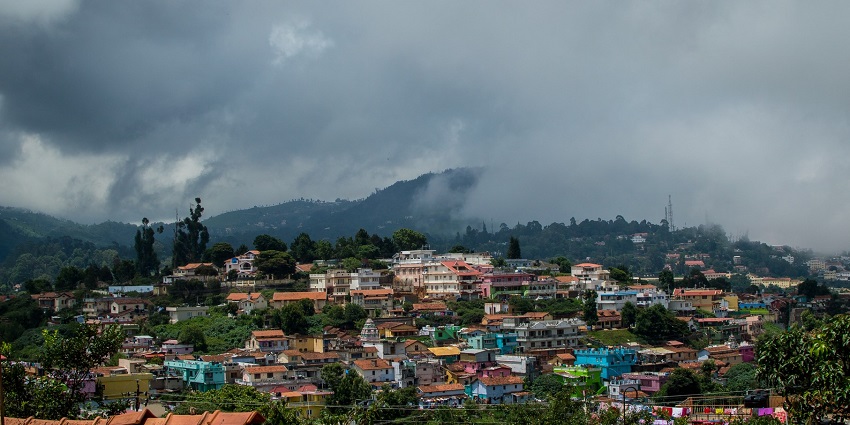 A foggy and cloudy day in Coonoor, with mist-covered hills and dense green vegetation.