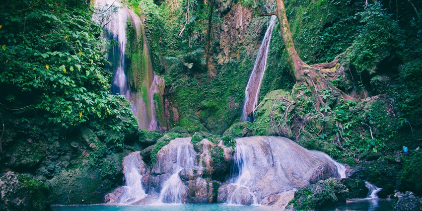 Courtallam Waterfalls cascading down rocky terrain surrounded by dense greenery.