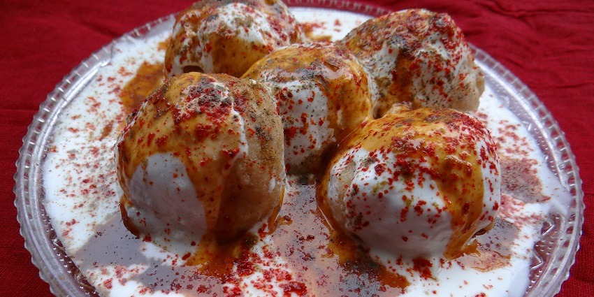 A picture of Dahi Bhalla served with chutney and with red chilli powder sprinkled