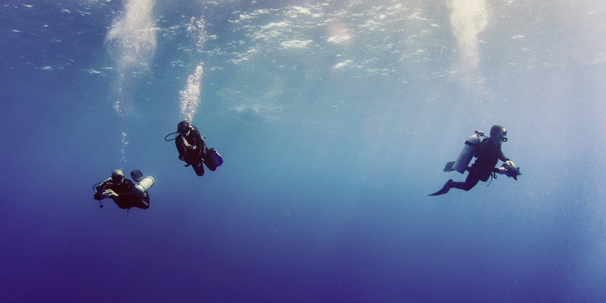 An image of a group of scuba divers in the turquoise waters of Dandeshwar