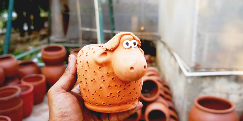 A picture of a person's fingers gripping a tiny ceramic sheep with big eyes.