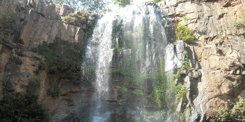 Scenic Dokrichanchara Waterfall cascading down rocky cliffs, surrounded by lush greenery