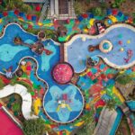 Aerial view of a vibrant swimming pool complex featuring colorful slides, surrounded by lounge chairs