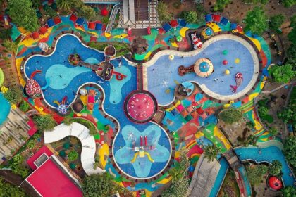 Aerial view of a vibrant swimming pool complex featuring colorful slides, surrounded by lounge chairs