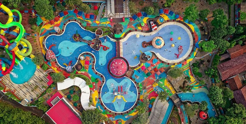 Aerial view of a vibrant swimming pool complex featuring colorful slides, surrounded by lounge chairs