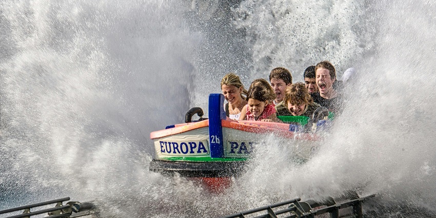 An image of people riding a boat on a serene lake or river in the water park.