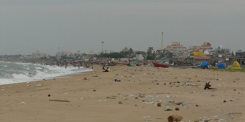 A sunny Besant Nagar Beach view with soft sand, gentle waves, and people enjoying the seaside.
