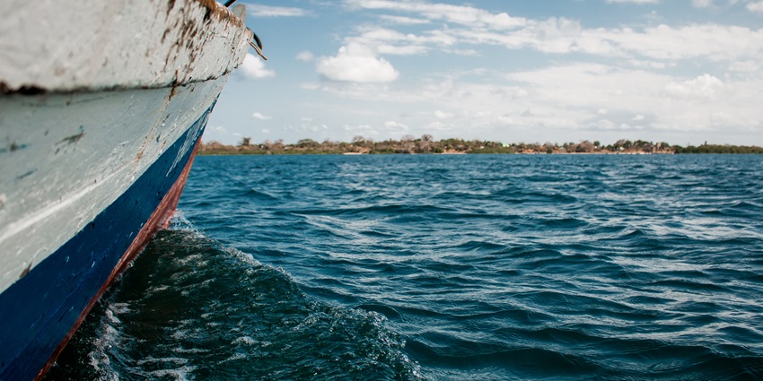 A picture of a boat sailing through the Chettinad Lake amidst the blue waters