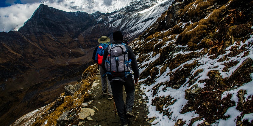 A glimpse of people trakking through the rustic terrains surrounded by majestic peaks.