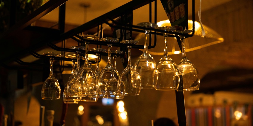 Elegant glasses hanging upside down from a rack in a bar, reflecting warm ambient lighting