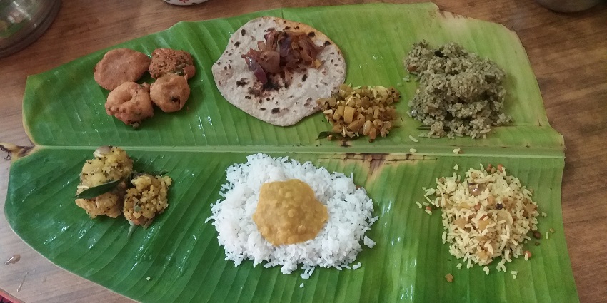 A variety of South Indian dishes served on a banana leaf at a restaurant.