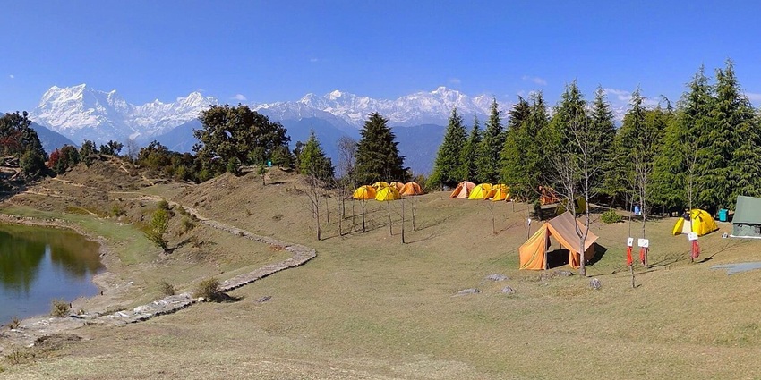 A picture of a lush green camping site with a lake nearby, camping where is one of the best things to do in Auli