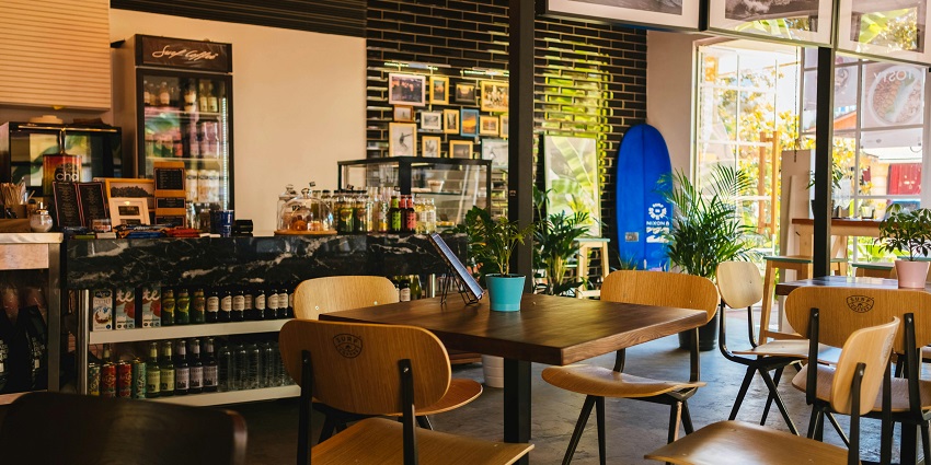 An inside view of a famous cafe with with planters, paintings, and scenic postcards.