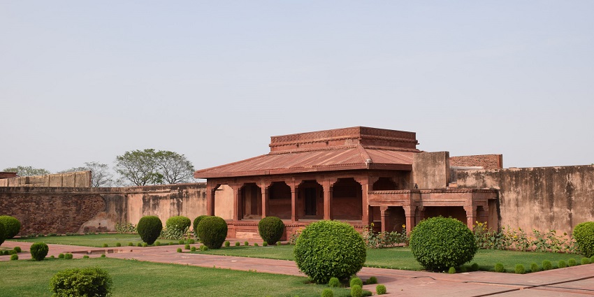 An image of a small wall encircled above the ground with flowers in Fatehpur Sikri.