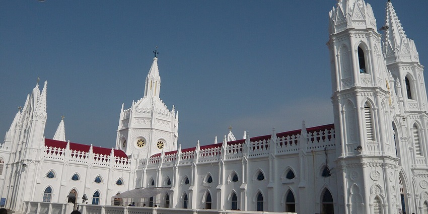 White Gothic architecture of Velankanni Temple with tall spires and intricate details.