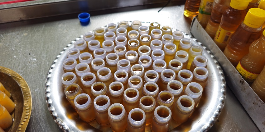 Containers of oil for temple rituals, placed on a tray, with opened bottle caps.