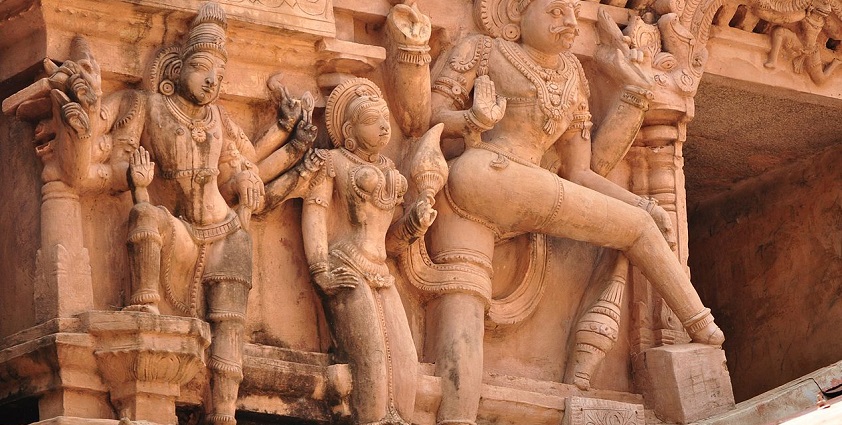Amorous statues at Tirumayam Temple with delicately carved figures into the stone walls.