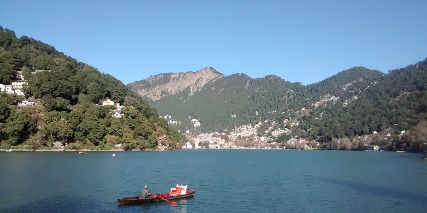 View of the tranquil beauty of Chenab Lake in Auli, with a boat sailing amidst it
