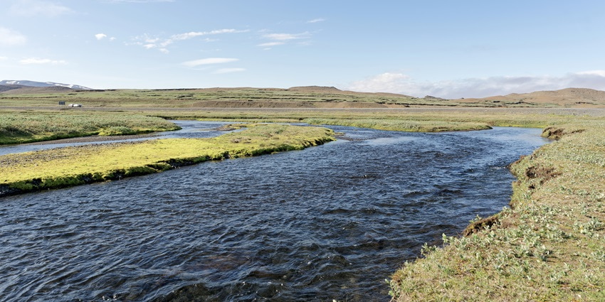 A picture of a river flowing through the scenic town of Karaikudi with greenery all around