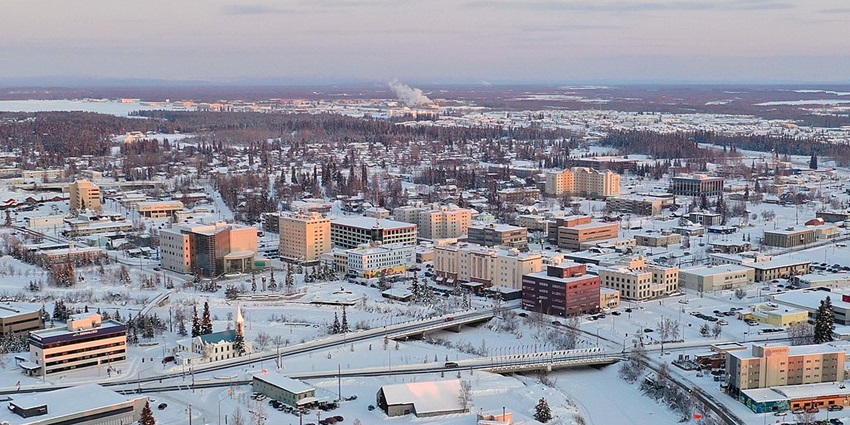 An aerial view of Fairbanks with buildings, roadways and trees covered in snow.