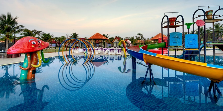 Image of a waterpark with colourful water slides and clear water pool around the palm trees