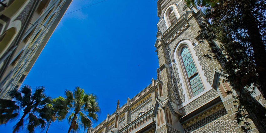 A peaceful cathedral interior featuring vaulted ceilings and intricate stained-glass windows.