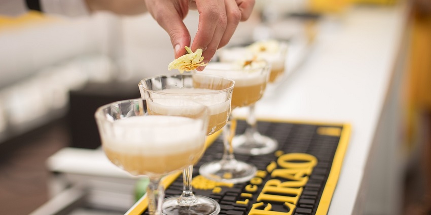 A picture of a bartender serving cocktails in assorted glasses