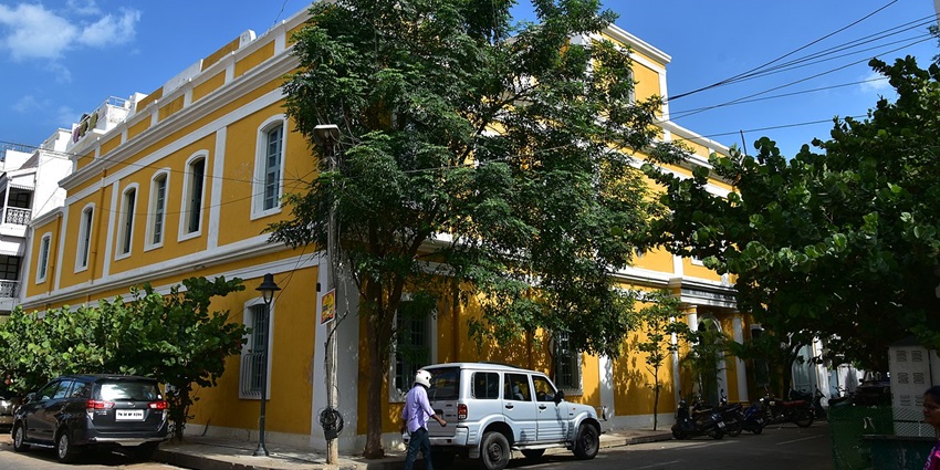 A view of a colourful French Quarter Street in Pondicherry with bright buildings and greenery.
