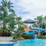 A view of the poolside with people relaxing on loungers and swimming in a waterpark.