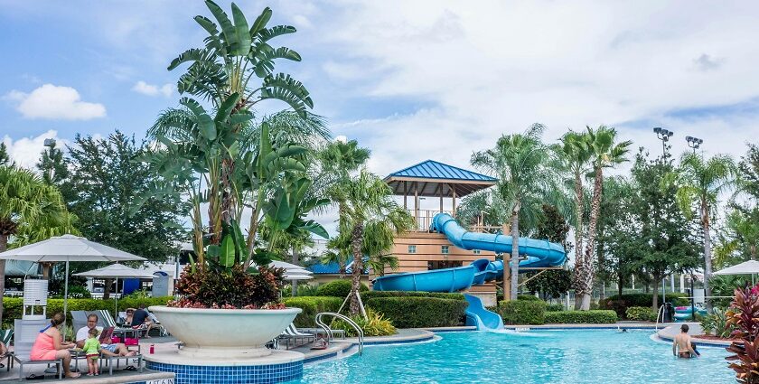 A view of the poolside with people relaxing on loungers and swimming in a waterpark.