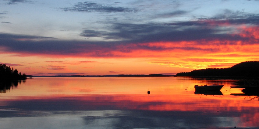 A view of Sunset with the sun casting its orange glow on the lake beneath and a boat in the lake
Viewers of this file can see comments and suggestions