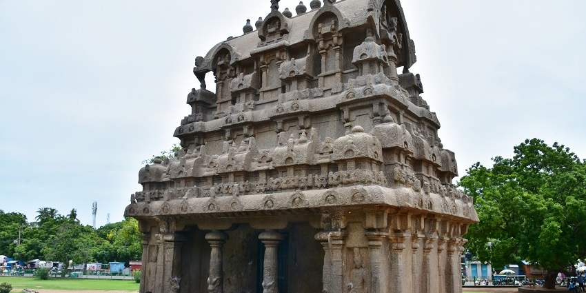 An outer view of the Ganesh Ratha Temple is showcased while a man is sitting outside it.
